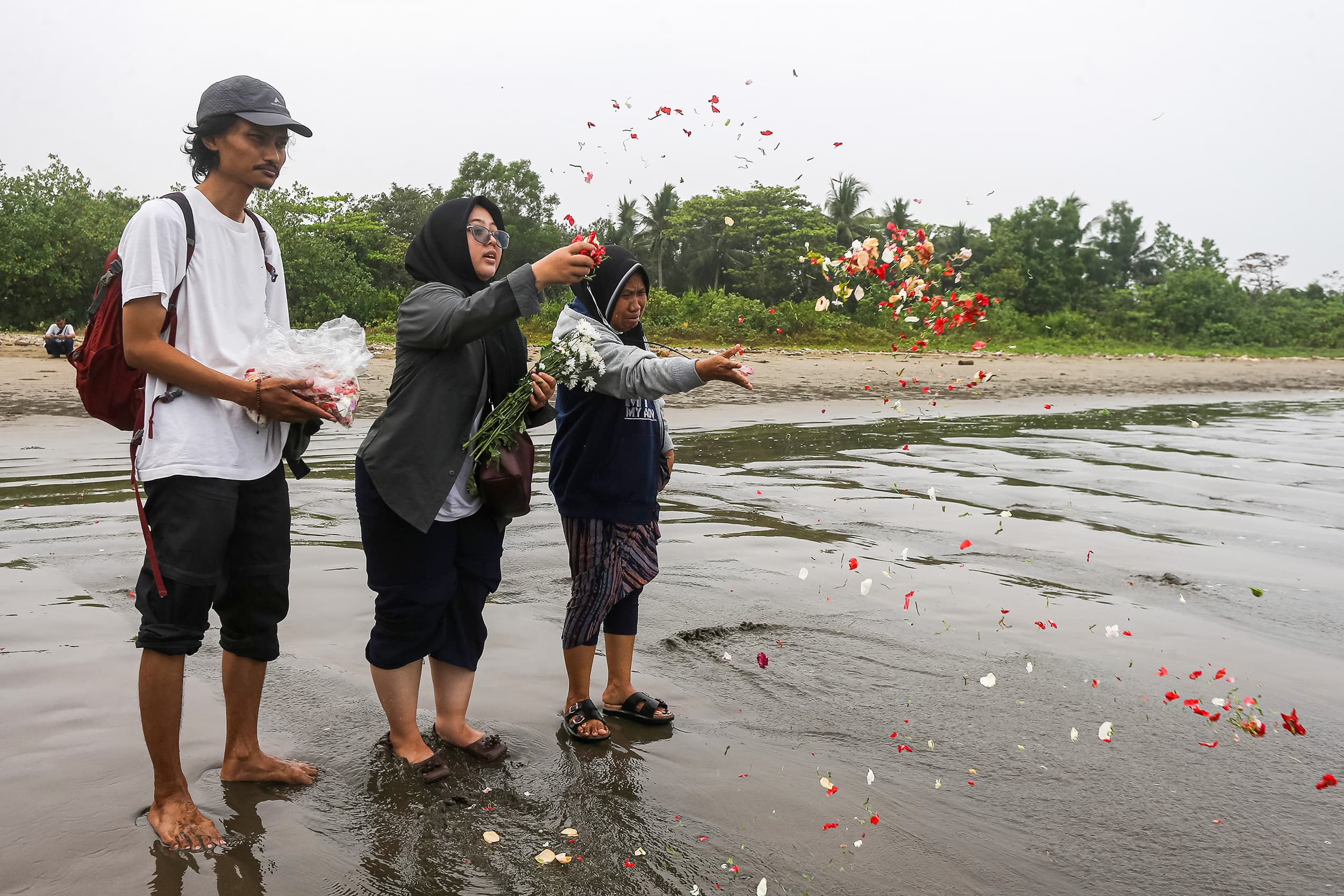 Istri dan ibu jurnalis ANTARA yang hilang kontak, M Bagus Khoirunas, Desi Purnama Sari (kiri), Tini (tengah) dan Korlip Antara Foto Sigid Kurniawan (kiri) berdoa usai melakukan tabur bunga di bibir Pantai Kampung Pagedongan, Carita, Pandeglang, Banten, Jumat (18/9/2026). ANTARA FOTO/Angga Budhiyanto/agr